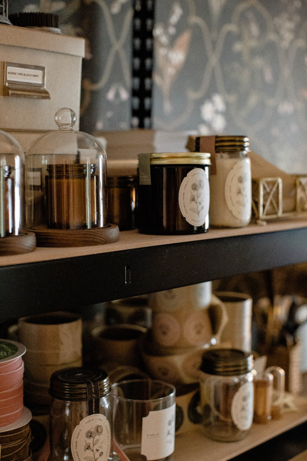 Amber Field + Bee candle jars and glass cloches on shelves in Rachel’s candle studio.